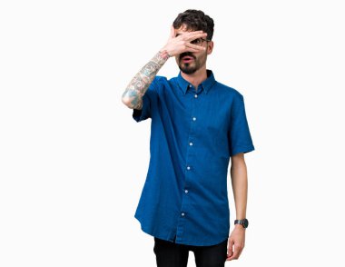 Mahcup ifadeyle parmaklarımın arasından seyir yüz ve gözler el ile kapsayan şok bakmak izole arka plan üzerinde gözlük takan genç yakışıklı adam.