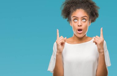 Genç afro Amerikalı kadın üzerinden hayran ve yukarıya bakıyor ve parmakları ile işaret ve silah kaldırdı sürpriz izole arka plan.