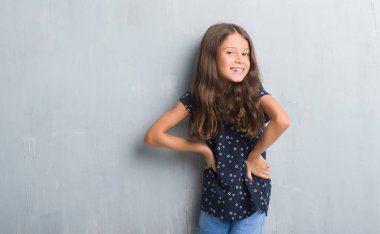 Grunge genç İspanyol çocuk gri duvar yüzündeki mutlu ve güzel bir gülümseme ile. Şanslı kişi.