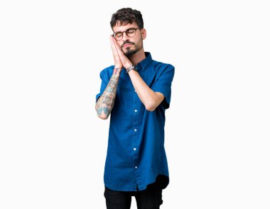 Uyku yorgun hayal ve ellerle birlikte poz ile kapalı gözler gülümseyen izole arka plan üzerinde gözlük takan genç yakışıklı adam.