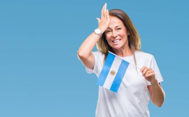 Orta yaş İspanyol kadın holding bayrağı Arjantin kafasına, utanç ve sürpriz ile şok el ile vurguladı izole arka plan üzerinde yüz, öfkeli ve sinirli. Korku ve hata için üzgün.