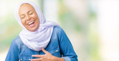 Orta yaş Doğu Arap kadın giyiyor Arap türban izole üzerinde arka plan gülen ve komik deli şaka çünkü yüksek sesle zor gülüyor. Mutlu ifade.