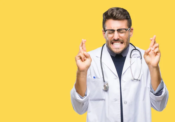 Joven Médico Guapo Sobre Fondo Aislado Sonriendo Cruzando Los Dedos — Foto de Stock