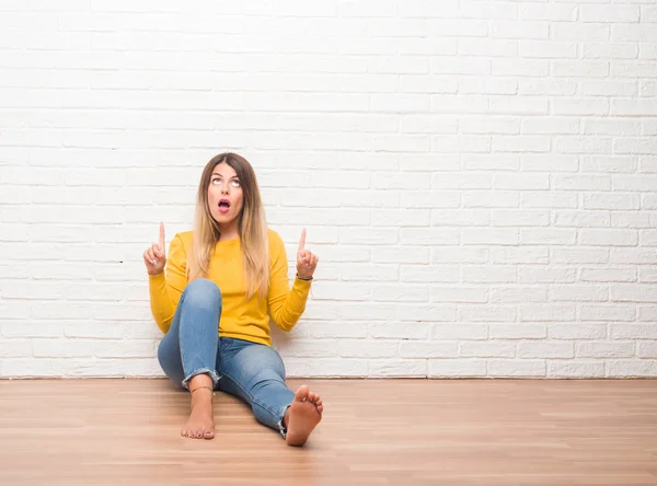 Mujer Adulta Joven Sentada Suelo Sobre Pared Ladrillo Blanco Sorprendida — Foto de Stock