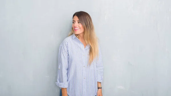 年轻的成年女子在灰色的格格格墙上穿着时尚商务服装 面带微笑望着一边 自然表情 笑自信 — 图库照片