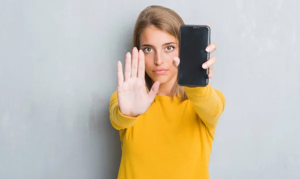 Vacker Ung Kvinna Över Grunge Grå Vägg Visar Smartphone Skärmen — Stockfoto