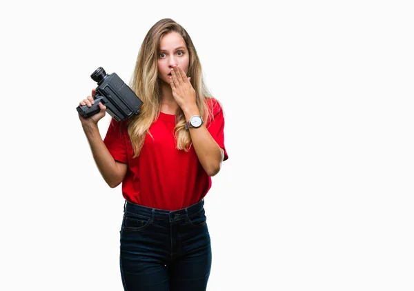 Young beautiful blonde woman filming using vintage camera over isolated background cover mouth with hand shocked with shame for mistake, expression of fear, scared in silence, secret concept