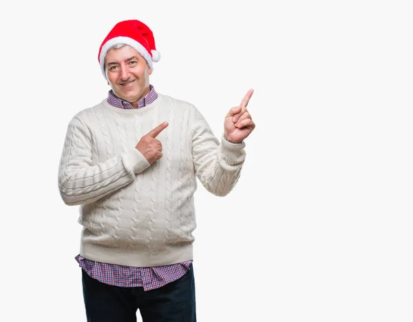 分離背景笑顔で側に つの手と指で指しているカメラ目線の上クリスマス帽子をかぶっているハンサムな年配の男性 — ストック写真