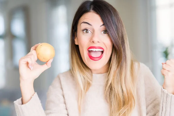 Jovem Mulher Bonita Segurando Batata Fresca Casa Gritando Orgulhoso Comemorando — Fotografia de Stock