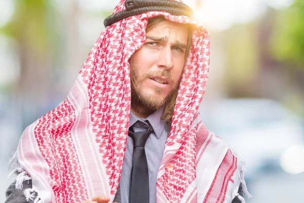 年轻英俊的阿拉伯男人带着长发穿着 Keffiyeh 在孤立的背景下反感表达 不高兴和害怕做厌恶的脸 因为反感反应 恼人的概念 — 图库照片