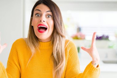 Evde çılgın ve kızgın bağırarak ve agresif ifade ve silah kaldırdı bağırmaya kış kazak giyen genç güzel kadın. Hayal kırıklığı kavramı.