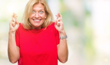 Orta yaş sarışın kadın geçiş parmakları umut ve gözler gülümseyen izole arka plan yüzünden kapalı. Şans ve batıl kavramı.