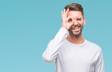 Genç yakışıklı adam gülümsüyor, parmakları ile mutlu yüz üzerinden seyir göz el ile ok jest yapıyor izole arka plan üzerinde.