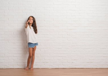 Tebrik ve konuksever dost sunan karşılıklı gülümseyen beyaz tuğla duvarın üzerinden genç İspanyol çocuk stading. Başarılı iş.