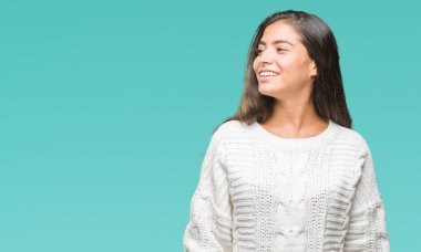 Üzerinde kış kazak giyen genç güzel Arap kadın arka plan uzak tarafına gülümseme ile yüzünde, doğal ifade arıyorum izole. Kendine güvenen gülüyor.