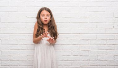 Genç İspanyol çocuk için beyaz tuğla duvar tiksinti ifadesi, memnun ve korkulu tiksinti yüz yapıyorsun çünkü nefret tepki. Elleriyle kaldırdı. Sinir bozucu kavramı.