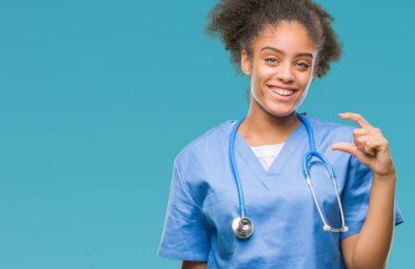 Genç afro Amerikalı doktor kadın izole arka plan gülümseyen ve boyutu işaret parmaklı ararken ve kamera işi el ile kendine güvenen el hareketi yüzünden. Ölçü kavramı.