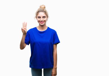 Gösterilen ve parmakları ile işaret izole arka plan üzerinde mavi t-shirt giyen genç güzel sarışın ve mavi gözlü kadın kendinden emin ve mutlu gülümseyerek iken üçüncü.