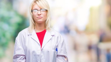 Yüzünde ciddi bir ifade ile izole arka plan üzerinde beyaz önlük giyen genç güzel sarışın profesyonel kadın. Basit ve doğal kameraya bakıyor.