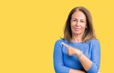 Orta yaş üzerinde kış kazak giyen güzel kadın izole arka plan el parmak ile gösterilen reklam, ciddi ve sakin yüz tarafına işaret