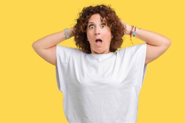 Üzerinde beyaz t-shirt giyen güzel orta ager üst düzey kadın arka plan deli izole ve baş, korkuyor ve açık ağzı ile şok sürpriz elleriyle korkuttu