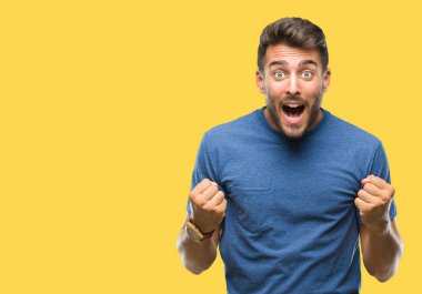 İzole arka plan kutlama üzerinde genç yakışıklı adam şaşırttı ve başarı için kaldırdı kollarını açarak hayret ve gözleri açık. Kazanan kavramı.