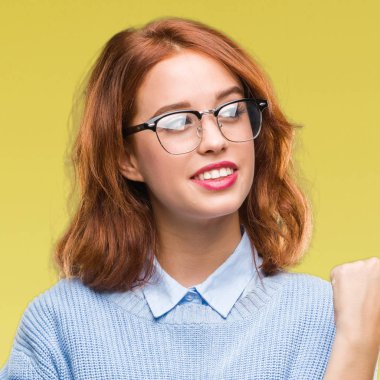 İzole arka planı arıyorum ve başparmak yanında yukarıyı mutlu yüz ile gülümseyen kış kazak giyen genç güzel kadın.