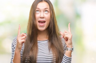 Genç güzel beyaz kadın üzerinden hayran ve yukarıya bakıyor ve parmakları ile işaret ve silah kaldırdı sürpriz izole arka plan.