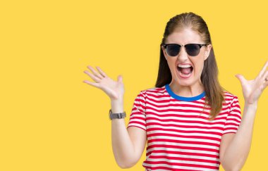 Orta yaş Olgun kadın üzerinde güneş gözlüğü takıyor deli kutluyor arka plan izole ve silah ile başarı için yükseltilmiş ve açık gözleri heyecanlı çığlık hayrete düşürdü. Kazanan kavramı