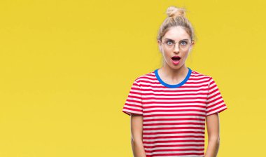 Korkuyor ve şok sürpriz ifade, korku ve heyecan yüz ile izole arka plan üzerinde gözlük takan genç güzel sarışın kadın.