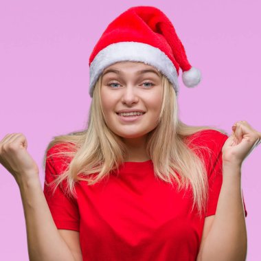 İzole arka plan kutlama üzerinde Noel şapka giyen genç beyaz kadın şaşırttı ve başarı için kaldırdı kollarını açarak hayret ve gözleri açık. Kazanan kavramı.