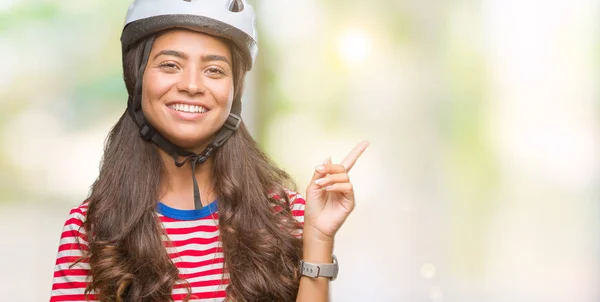 年轻的阿拉伯自行车运动员戴着安全帽 脸上带着灿烂的笑容 用手和手指指着一旁看着镜头 — 图库照片
