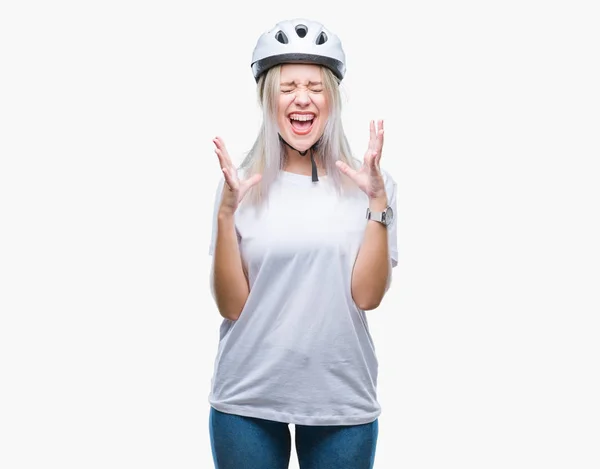 年轻的金发女子穿着自行车安全头盔在孤立的背景下庆祝疯狂和疯狂的成功与手臂举起 闭上眼睛尖叫兴奋 赢家理念 — 图库照片