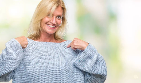 中年金髪女性の顔に笑顔と自信を持って 誇りと幸せな指で自分を指している孤立した背景に冬のセーターを着て — ストック写真