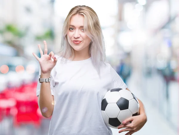 年轻的金发女子拿着足球在孤立的背景做确定的标志与手指 优秀的象征 — 图库照片