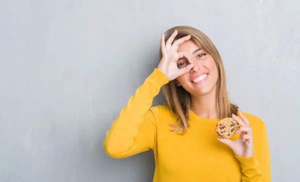 Hermosa Joven Mujer Sobre Grunge Gris Pared Comer Chocolate Chip —  Fotos de Stock