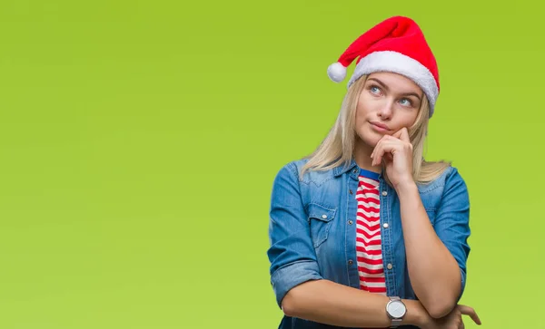 若い白人女性のあごを考えて質問 物思いにふける式の手で隔離された背景にクリスマス帽子をかぶっています 思いやりのある顔をして笑っています 疑いのコンセプト — ストック写真