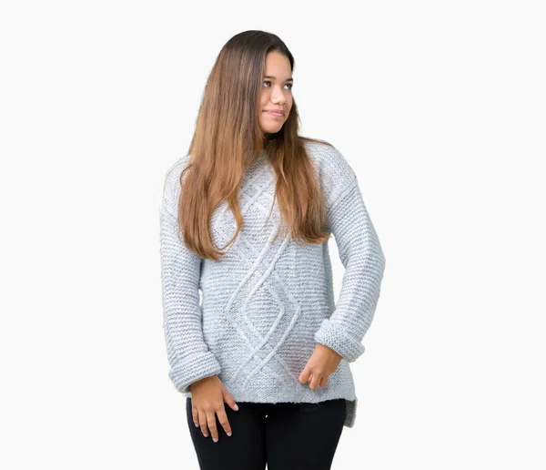 若い美しいブルネット女性の自然な表現の顔に笑みを浮かべて側に離れて見て孤立の背景の上にセーターを着ています 自信を持って笑ってください — ストック写真