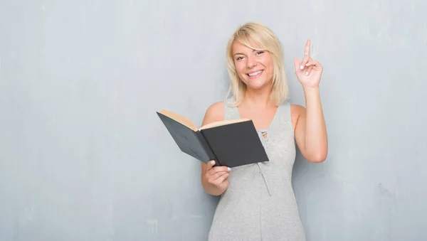 Mujer Adulta Caucásica Sobre Pared Grunge Gris Leyendo Libro Sorprendido — Foto de Stock