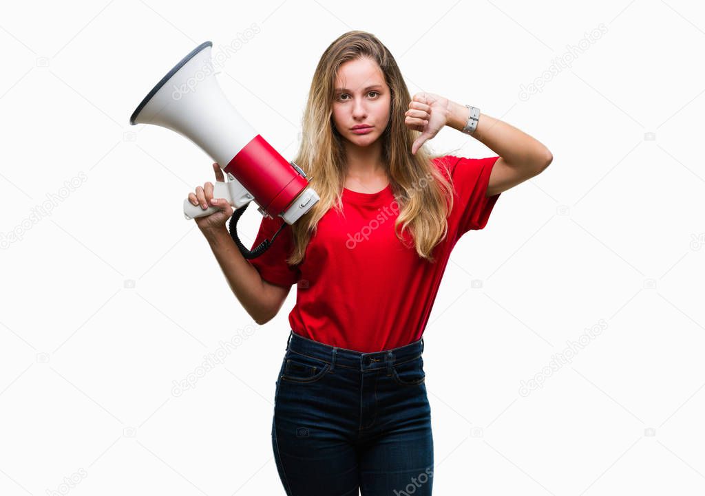 Young beautiful blonde woman yelling through megaphone over isolated background with angry face, negative sign showing dislike with thumbs down, rejection concept