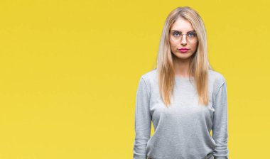 Yüzünde ciddi bir ifade ile izole arka plan üzerinde gözlük takan genç güzel sarışın bir kadın. Basit ve doğal kameraya bakıyor.
