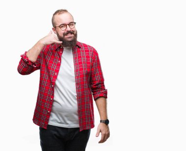 İşin gülümseyen izole arka plan üzerinde gözlüklü Genç beyaz hipster adam telefon hareketi ile el ve parmak telefonda konuşuyor gibi. Kavramları iletişim.