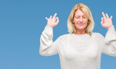 Kış relax arka plan izole kazak giyen ve gülümseyen gözlerle orta yaş sarışın kadın meditasyon jest parmak ile yapıyor kapalı. Yoga kavramı.