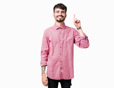 Yakışıklı delikanlı gösterilen ve kendinden emin ve mutlu gülümseyen bir parmak ile işaret eden oktan yukarı izole arka plan üzerinde pembe gömlek giymiş.