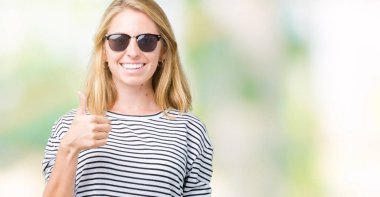 Güzel genç kadın hareketi el ile mutlu yaşasın yapıyor izole arka plan üzerinde güneş gözlüğü takıyor. Kameraya bakarak başarı gösteren ile ifade onaylama.