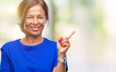 Kameraya bakarak yan el ve parmak ile işaret orta yaş İspanyol kadın kıdemli yüzünde kocaman bir gülümseme ile izole arka plan üzerinde.