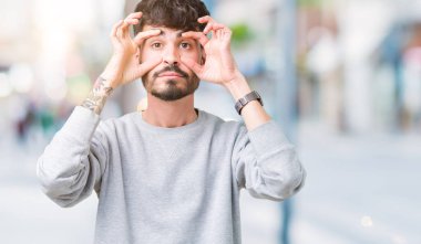 Parmaklarıyla, Uykulu ve sabah yorgunluk için yorgun gözlerini açmaya çalışırken izole arka plan üzerinde sweatshirt giyen genç yakışıklı adam