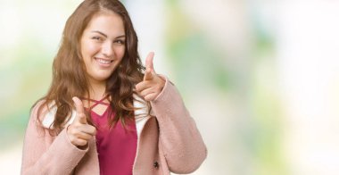 Artı boyutu genç kadın güzel üzerinde kış palto giyiyor için fotoğraf makinesi ile mutlu ve komik yüz parmakları işaret arka plan izole. İyi enerji ve vibes.