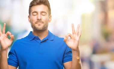 Yakışıklı delikanlı izole arka plan üzerinde dinlenmek ve gülümseyen gözlerle parmak ile meditasyon jest yapıyor kapalı. Yoga kavramı.