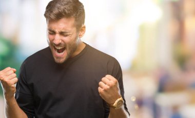 Soyutlanmış, mutlu ve heyecanlı genç bir adam kollarını kaldırmış, gülümseyen ve başarı için çığlık atan kazanan bir jest yapıyor. Kutlama konsepti.